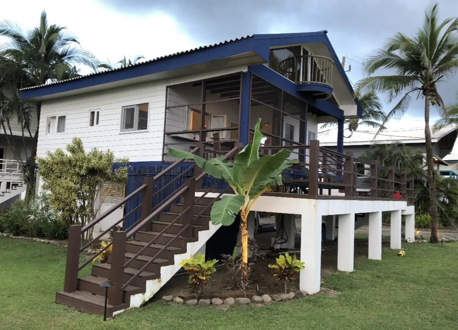 A raised wooden beach bungalow surrounded by palms