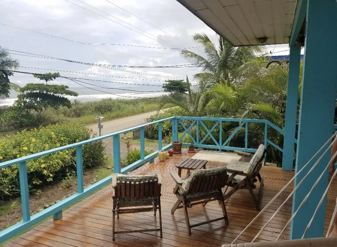 A covered wooden deck looking out to the beach