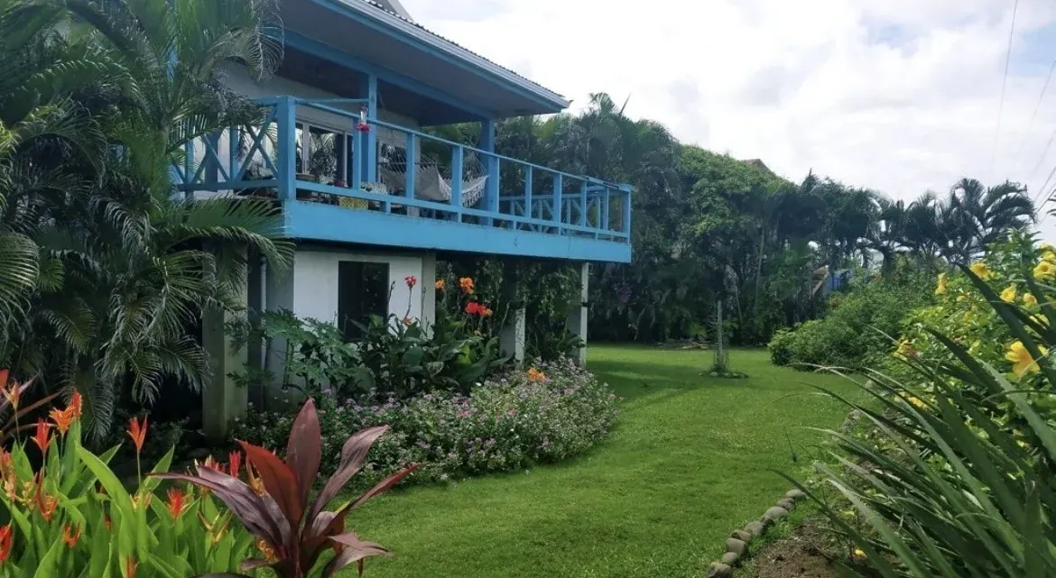 A two-storey beach house above a green lawn
